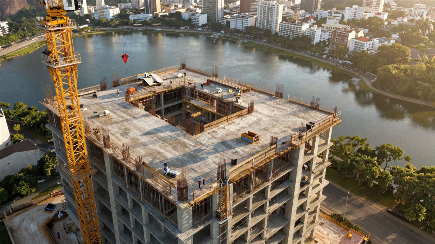 Vista aérea de um prédio em construção com guindaste, ao lado de uma lagoa no Rio de Janeiro